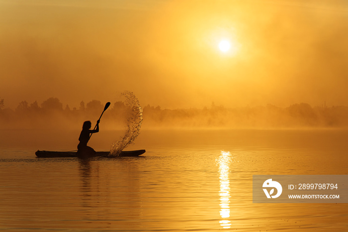 Active male paddler training on sup board during sunrise