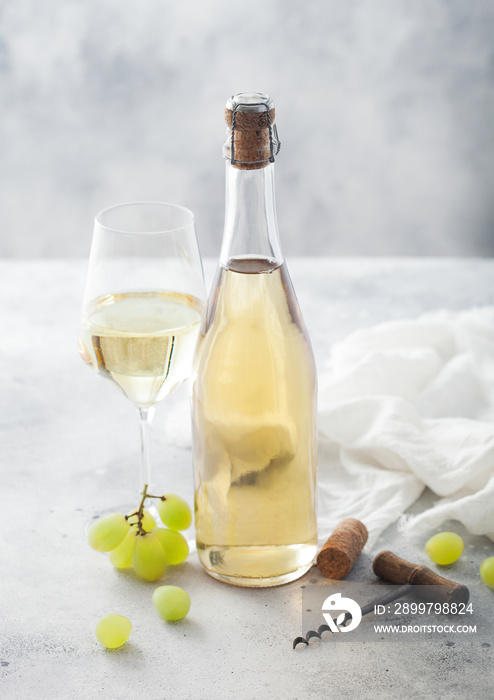 一瓶又一杯自制白葡萄酒，配葡萄和开瓶器，浅底亚麻布