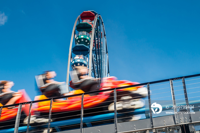 Ferris wheel and roller coaster in motion in amusement park