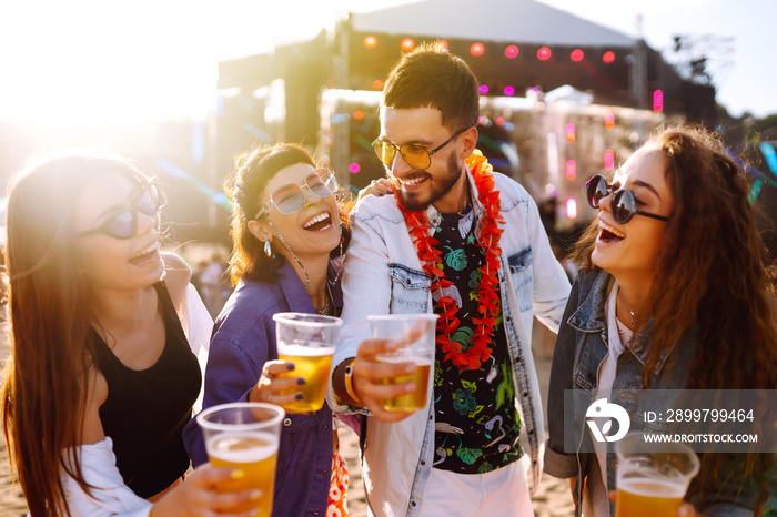 Young happy friends drinking beer and having fun at music festival together. Beach party, summer hol