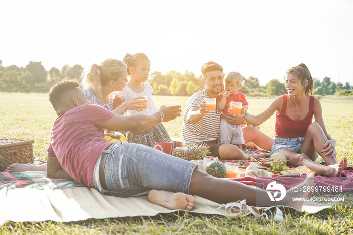 Happy families doing picnic in city park - Young parents having fun with their children in summer ti