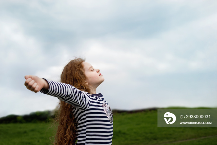 Little girl closed her eyes and breathing with fresh blowing air.