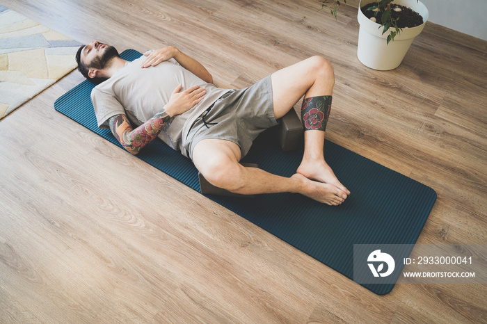 Young man meditating and deep breathing on yoga mat. Man doing diaphragmatic breathing exercise