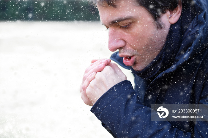 Man breathing on his hands to keep them warm