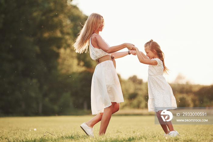 Dancing together. Mother and daughter enjoying weekend together by walking outdoors in the field. Beautiful nature