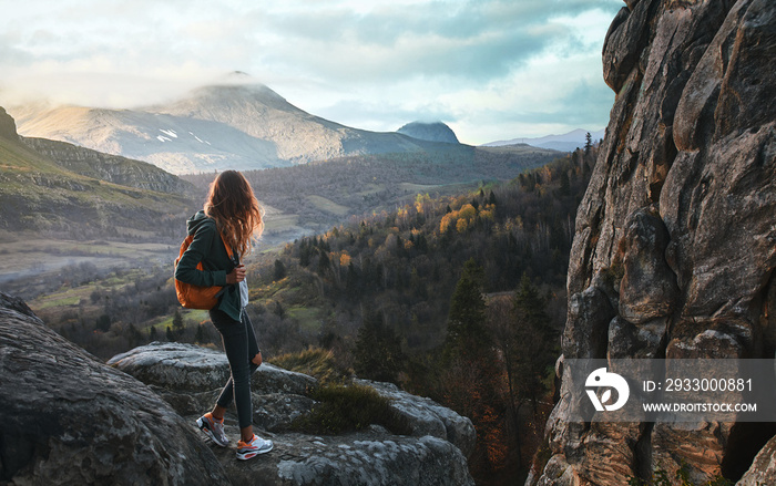 woman standing on edge of cliff against background of sunrise