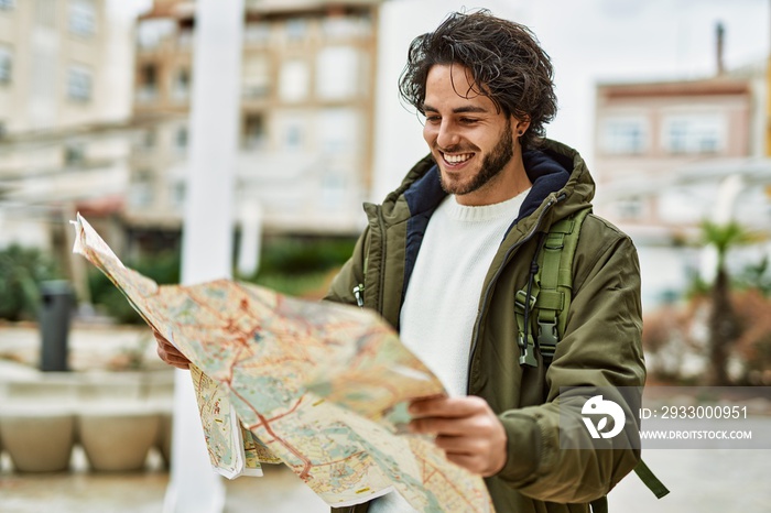 Handsome hispanic man looking at travel map at the city