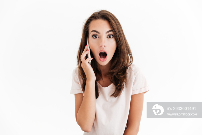 Shocked brunette woman talking by the smartphone