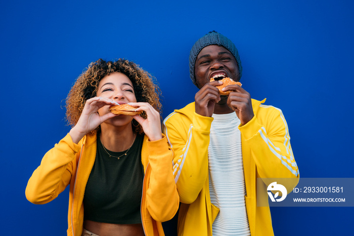 Young couple eating burger outdoors