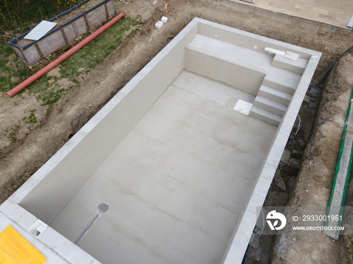 aerial drone shot of pool construction site almost finished spackling from above in a garden