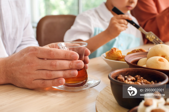 Man with cup of hot Turkish tea at table during breakfast. Celebration of Eid al-Fitr