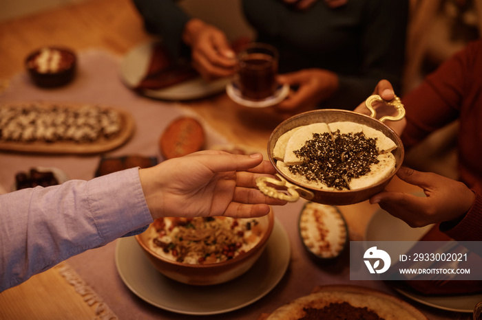 Close up of Muslim father and daughter passing food during family dinner at dining table.