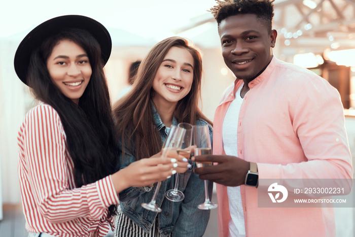 Portrait of beaming ladies and satisfied male tasting alcohol liquid while looking at camera during celebration