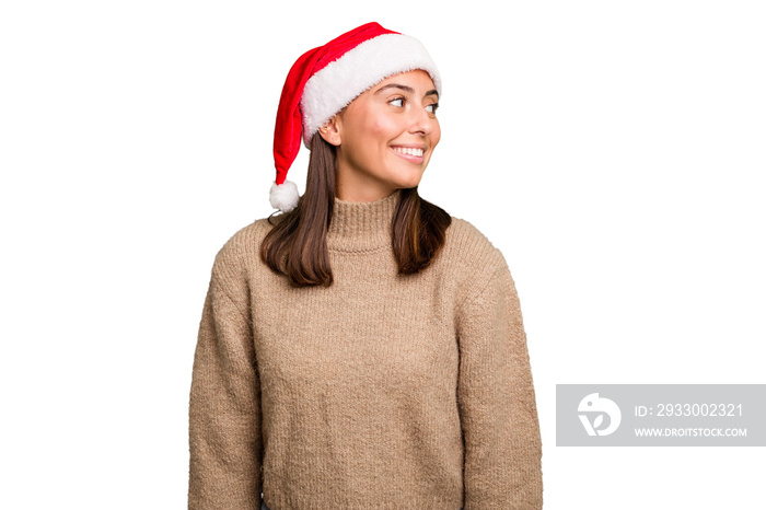 Young caucasian woman celebrating christmas wearing a santa hat isolated looks aside smiling, cheerful and pleasant.