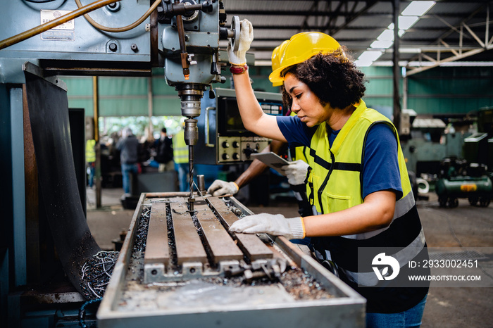 Women workers or mechanics in safety uniforms are working on metal drilling machines in industrial production lines, steel processing industry, mechanical maintenance.