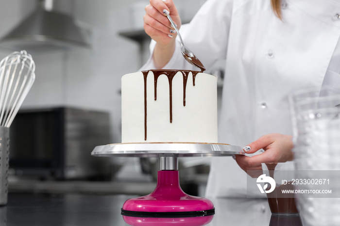 Pastry chef decorates the cake with chocolate streaks