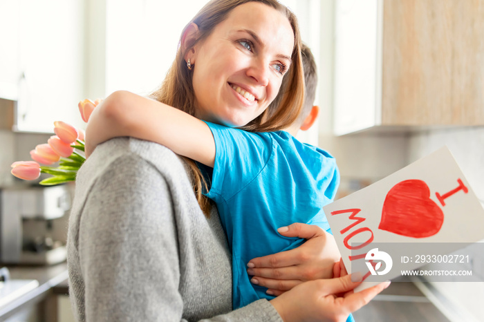 Son congratulates mom and gives her card and a bouquet of flowers to tulips