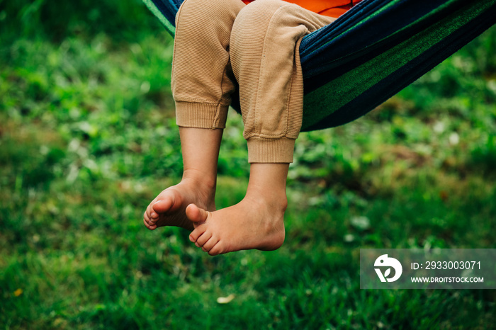 Closeup view on boy legs who sit hammock in outdoor