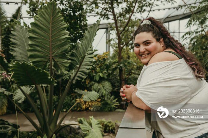 plus size woman leans on railing and looks at camera