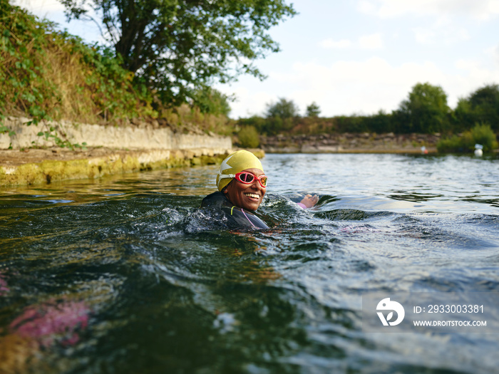 Woman in swimming cap and goggles swimming in river