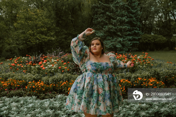 portrait of a plus size woman wearing a floral dress in a flower garden