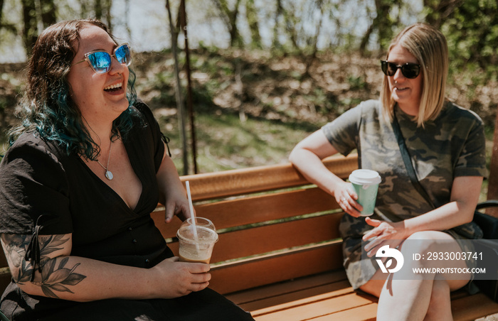 2 women sit on a bench talking and laughing