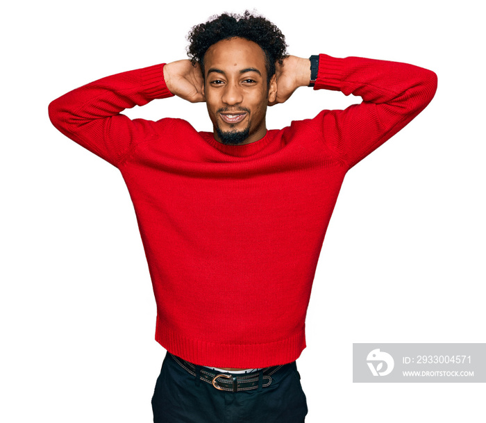 Young african american man with beard wearing casual winter sweater relaxing and stretching, arms and hands behind head and neck smiling happy