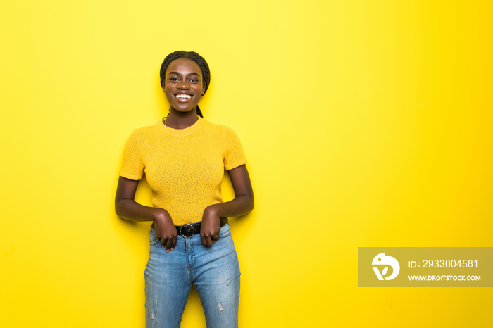 Beauty portrait of young african american girl posing on yellow background, looking at camera, smiling. Studio shot.