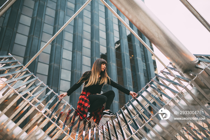 Happy young woman doing poses in a metal sculpture .