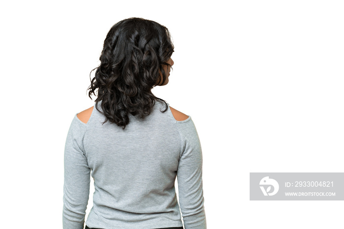 Young Argentinian woman over isolated background in back position and looking side