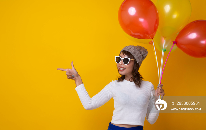 Asian woman smiling happily with colorful balloons on yellow background. Celebrate the party and congratulate