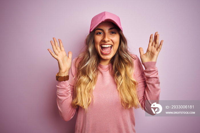 Young beautiful woman wearing cap over pink isolated background celebrating crazy and amazed for success with arms raised and open eyes screaming excited. Winner concept