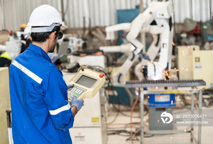 Caucasian technician engineer man use remote control with checking machine arm robot at factory