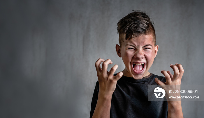 Teen boy screaming in anger on dark background