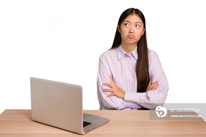 Young student asian woman in a workplace with a laptop isolated tired of a repetitive task.