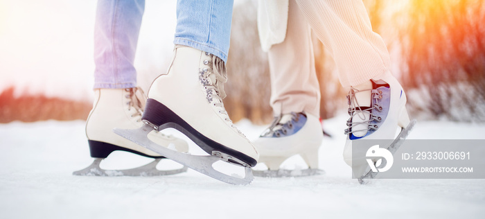 Banner Closeup two women wearing white ice skates on winter sunset background