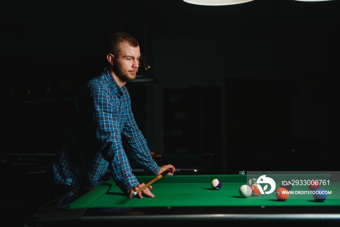 Thoughtful man plays billiards. Billiard room on the background.