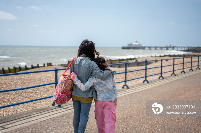 Mother and daughter (8-9) hugging on promenade