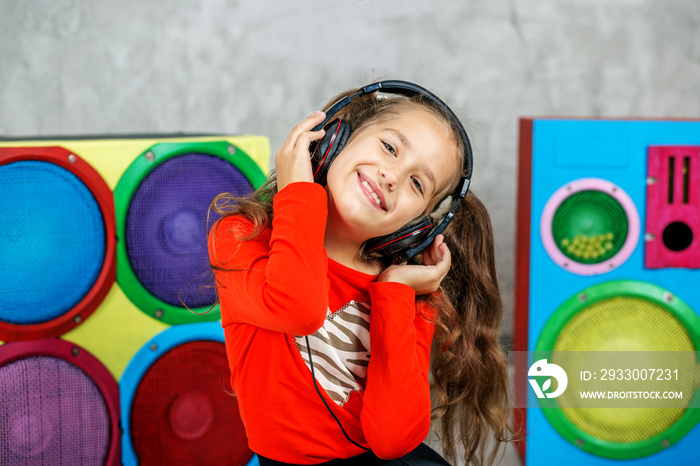 Cheerful child girl listens to a song with headphones. Concept music, radio, dance, life stroke, rest.