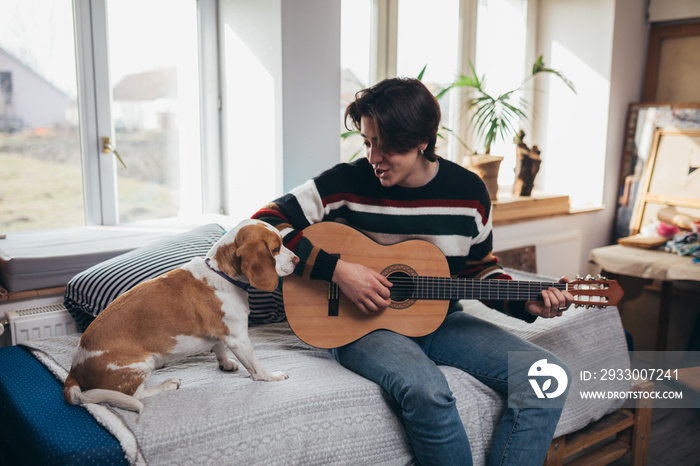 young man playing guitar at home