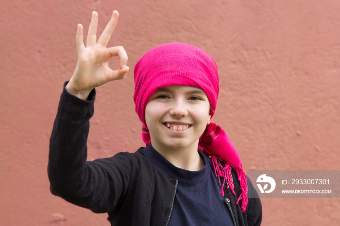 girl sick with cancer with head scarf and making ok sign with hands