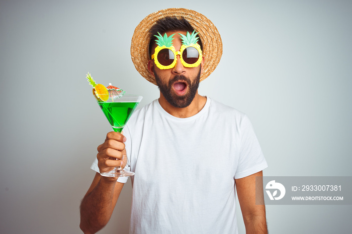 Indian man wearing summer funny look drinking cocktail over isolated white background scared in shock with a surprise face, afraid and excited with fear expression