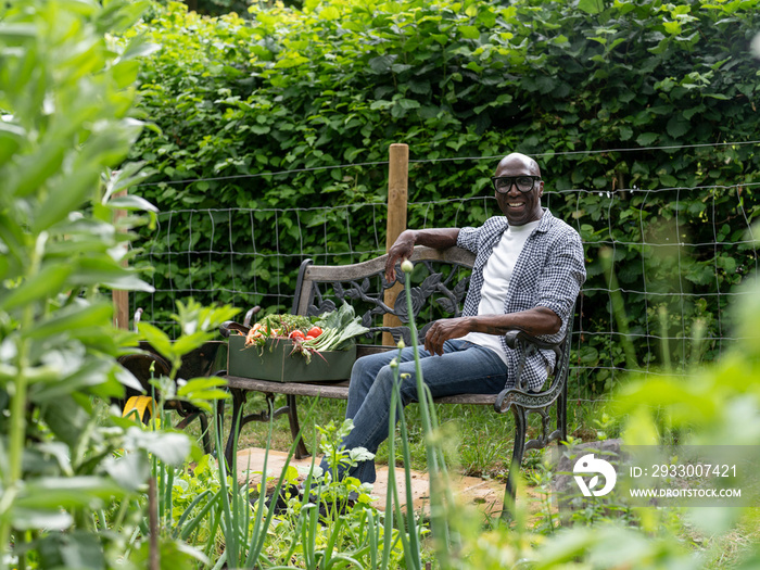 Smiling mature man resting on bench after working in garden