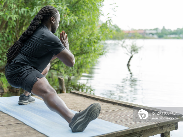 Man practicing yoga by lake