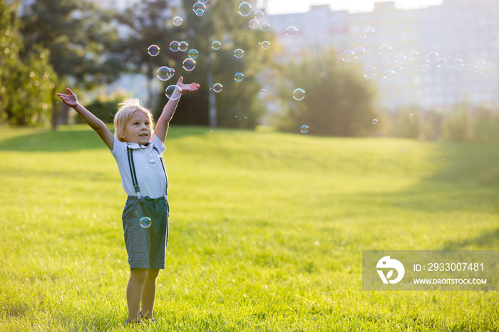 Cute preschool blond child, playing in the park on sunset, summertime