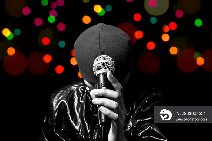 bw asian vocalist holding dynamic microphone with colourful bokeh in concert for music or singing contest background