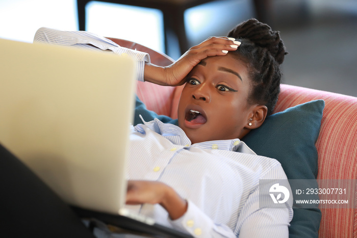 Woman watching laptop in disbelief