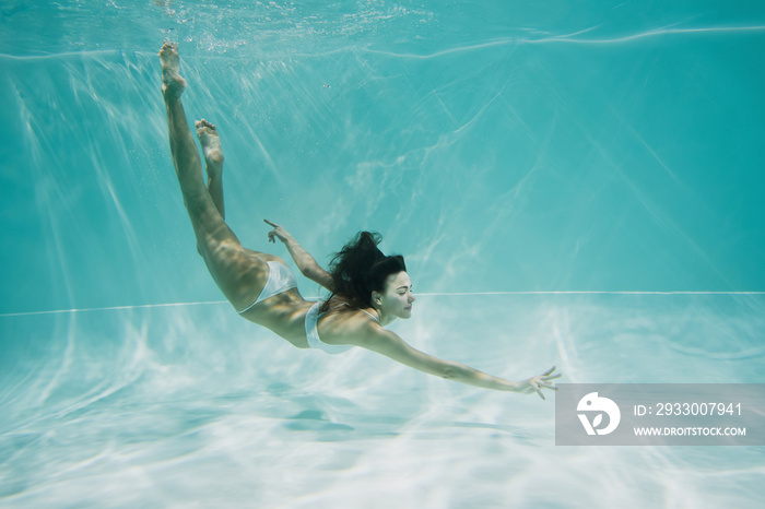 graceful woman in white swimsuit diving in swimming pool