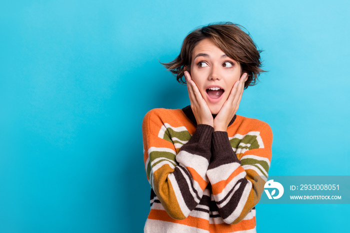 Photo of astonished girl with short hairstyle dressed striped pullover look empty space palms cheekbones isolated on blue color background