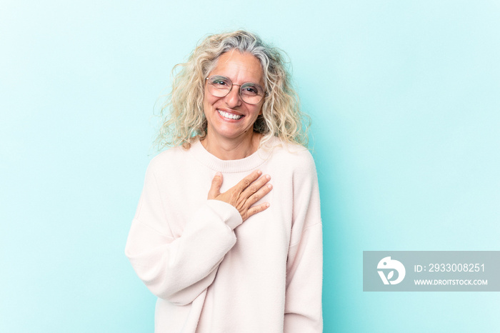 Middle age caucasian woman isolated on blue background laughing keeping hands on heart, concept of happiness.